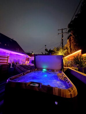 Un jacuzzi con panel de control, rodeado de mobiliario y plantas de exterior.