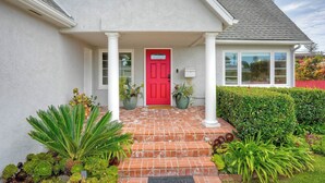 Una casa con puerta roja, columnas blancas y entrada de ladrillo.