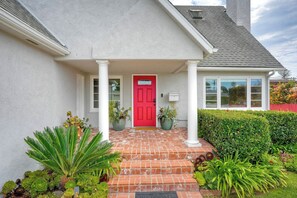 A house with a red door, white columns, and a brick entrance.