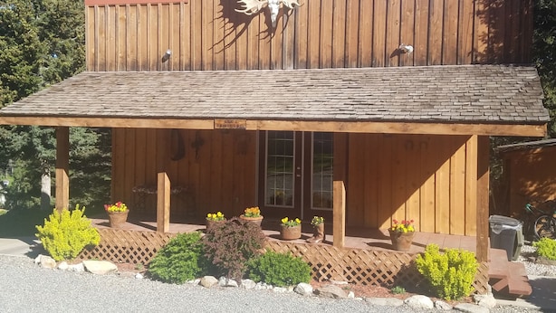Ein rustikales Holzhaus mit geneigtem Dach, einem aufgehängten Hirschschädel und einem Holzzaun.