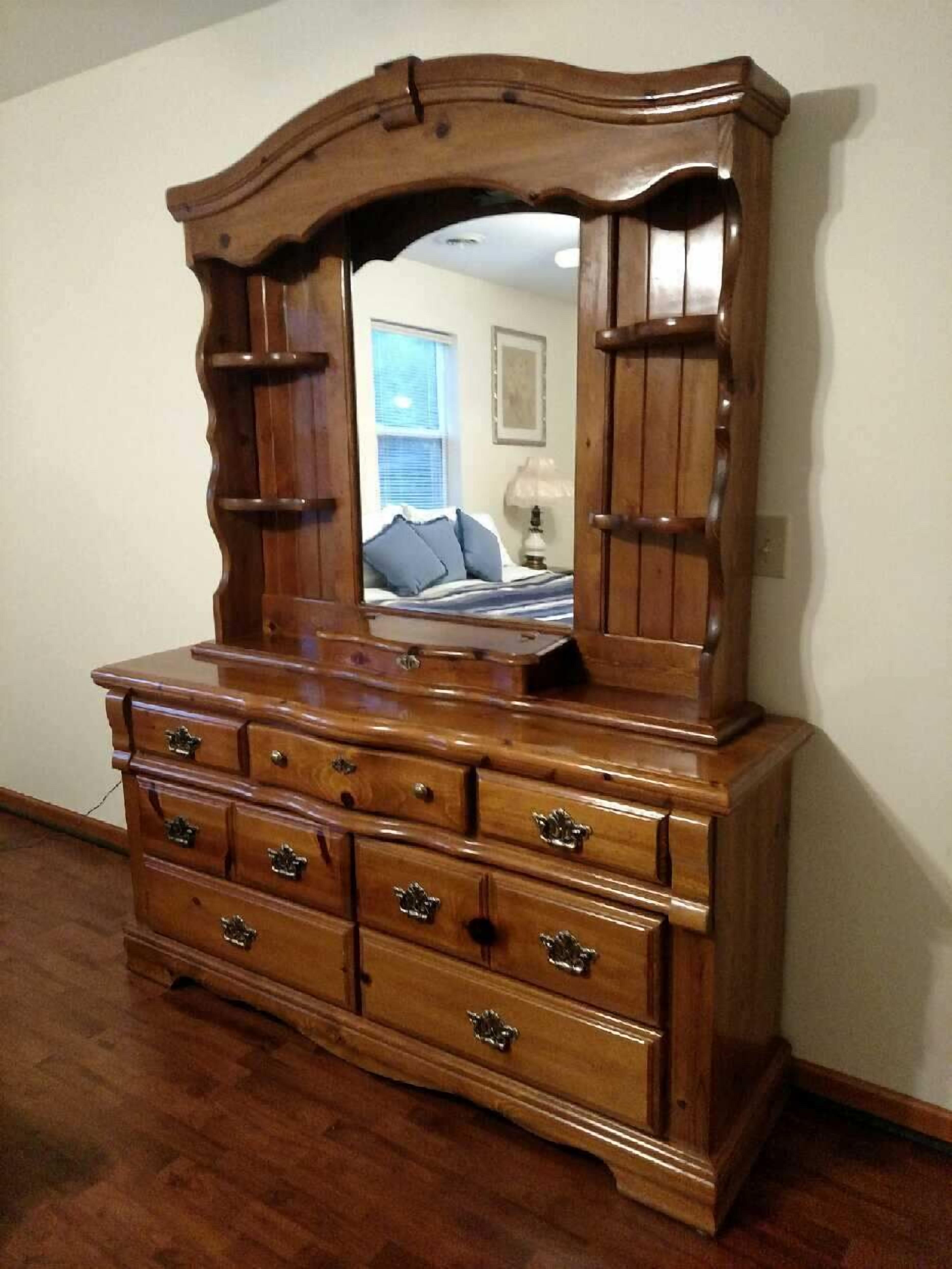 A wooden dresser with a mirror, multiple drawers, and a mirror cabinet.