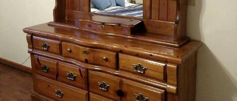 A wooden dresser with a mirror, multiple drawers, and a mirror cabinet.
