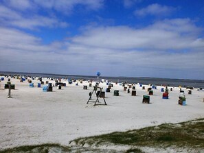 Una playa con numerosos contenedores de colores dispersos sobre la arena.
