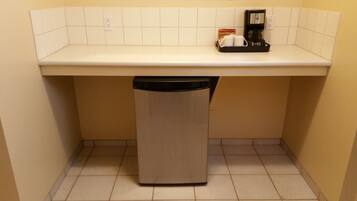 A compact kitchen with a dishwasher, a coffee maker, and a small countertop.