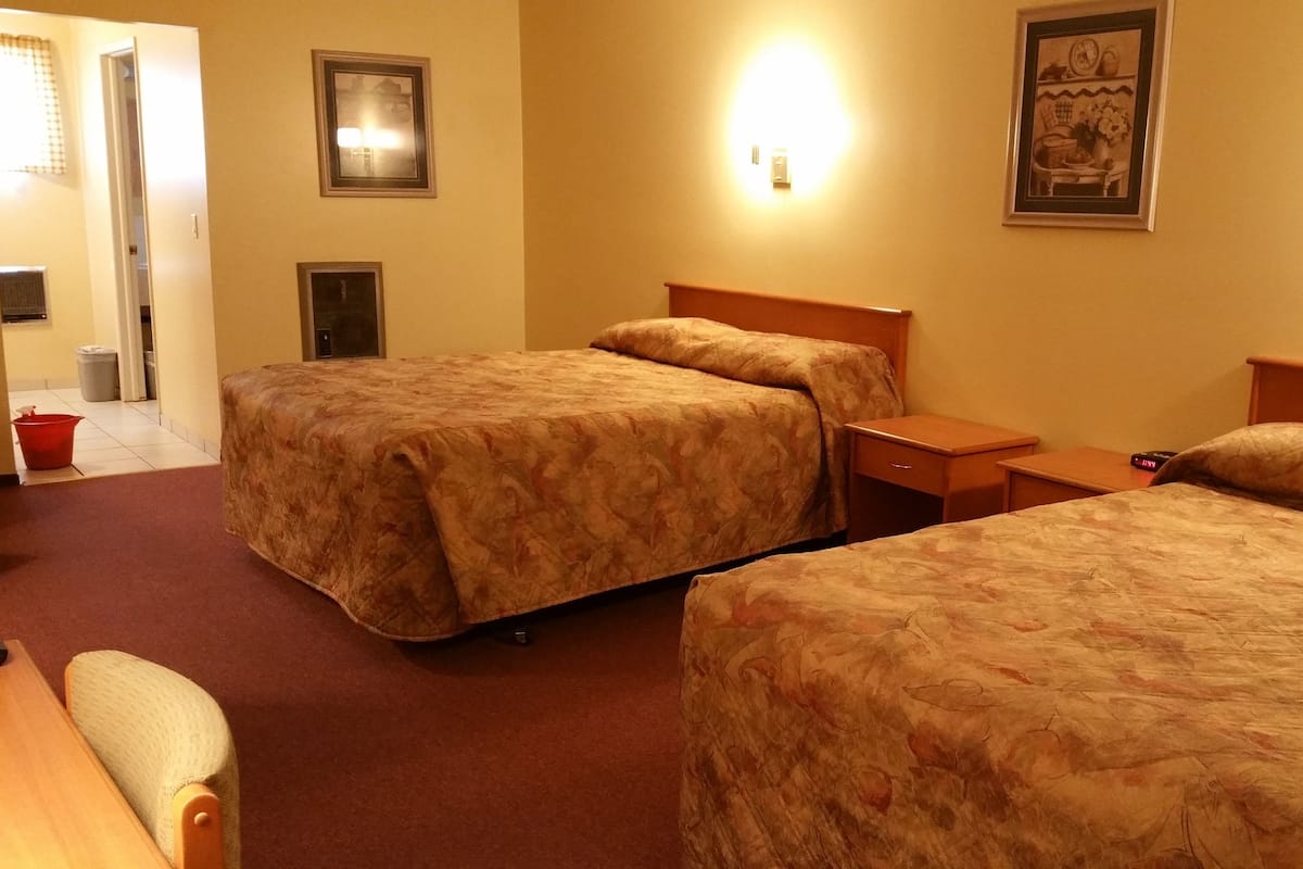 Una habitación de hotel con dos camas, una mesita de noche, una silla y una pequeña mesa.