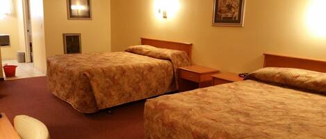 A hotel room with two beds, a nightstand, a chair, and a small table.