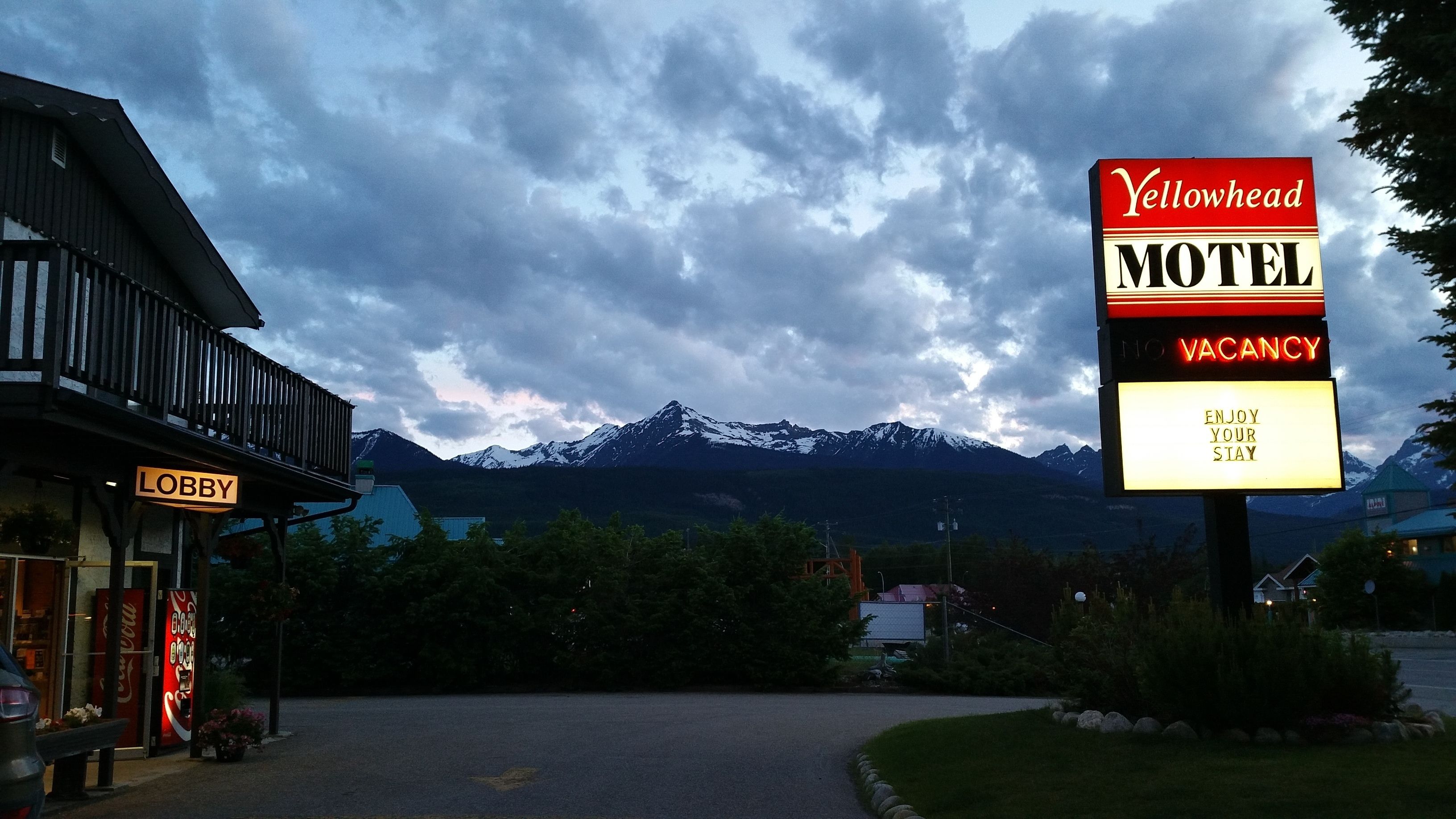 A motel sign with a mountain backdrop, a lobby sign, and a Coca-Cola sign.