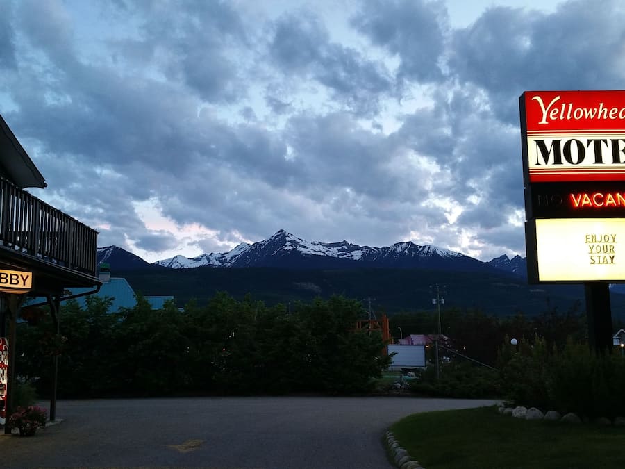 A motel sign with a mountain backdrop, a lobby sign, and a Coca-Cola sign.