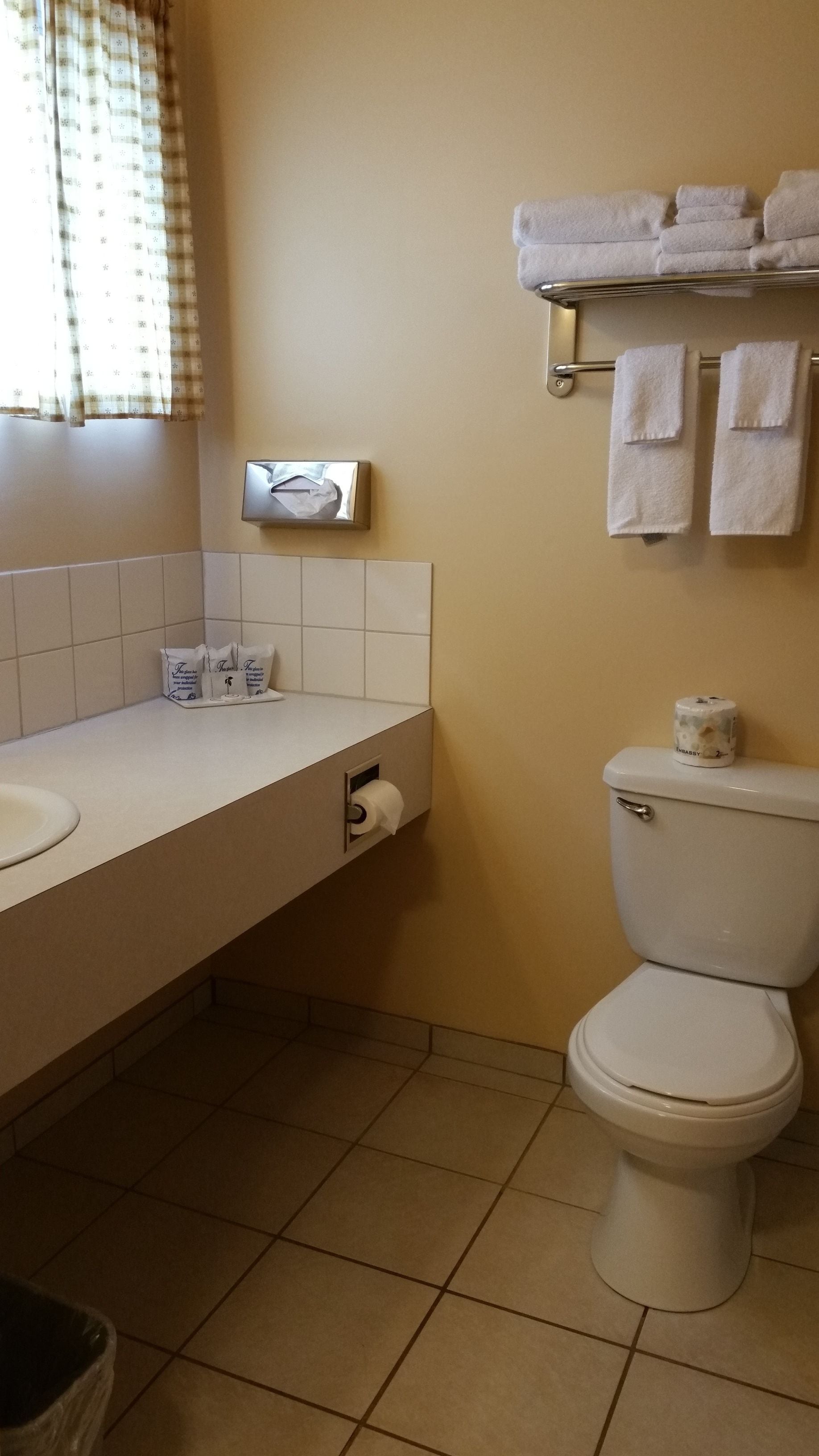 Un baño con un lavamanos blanco, un inodoro y un perchero con toallas dobladas.