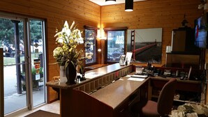 Et træinteriør med en receptionsdisk, en blomstervase, et stort vindue med udsigt til Golden Gate Bridge, og et fjernsyn.