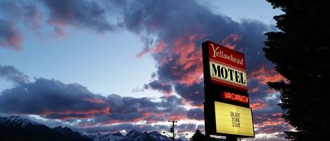 Une enseigne de motel indiquant « Complet », avec en arrière-plan un ciel spectaculaire au coucher du soleil et des montagnes enneigées.