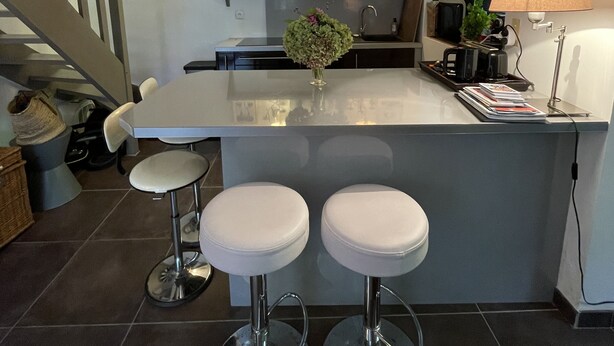 A modern kitchen with a central island, two bar stools, a microwave, and a coffee maker. - Charming old quiet house with garden - Village and sea on foot (Arradon)