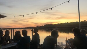 A group of people dining at an outdoor table with a view of a sunset over a body of water. - Charming old quiet house with garden - Village and sea on foot (Arradon)