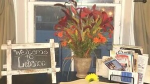 A window with a view of a clock tower, a welcome sign, a vase with flowers, and some books on a desk. - Beautiful, remodeled penthouse in Lebanon Ohio, between Dayton and Cincinnati (Lebanon)