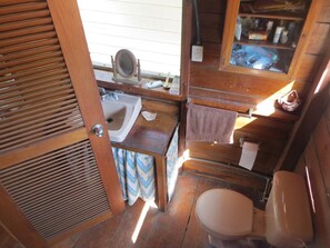 A compact wooden bathroom with a sink, toilet, and a mirror. - Casa Mascarona Miramar Beach Cabin (Nagarote)