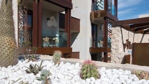 A modern building with a patio area featuring white pebbles and various cacti. - Alhambra Boutique  (San Bartolomé de Tirajana)