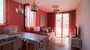A modern living room with a sofa, a coffee table, and a dining area with a patterned tablecloth. - Alhambra Boutique  (San Bartolomé de Tirajana)