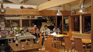 A cozy room with wooden furniture, a dining table, and various musical instruments. - Pension Tengallonhat (Matsumoto)