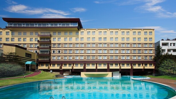 Un hotel con piscina, varios pisos y techo plano.