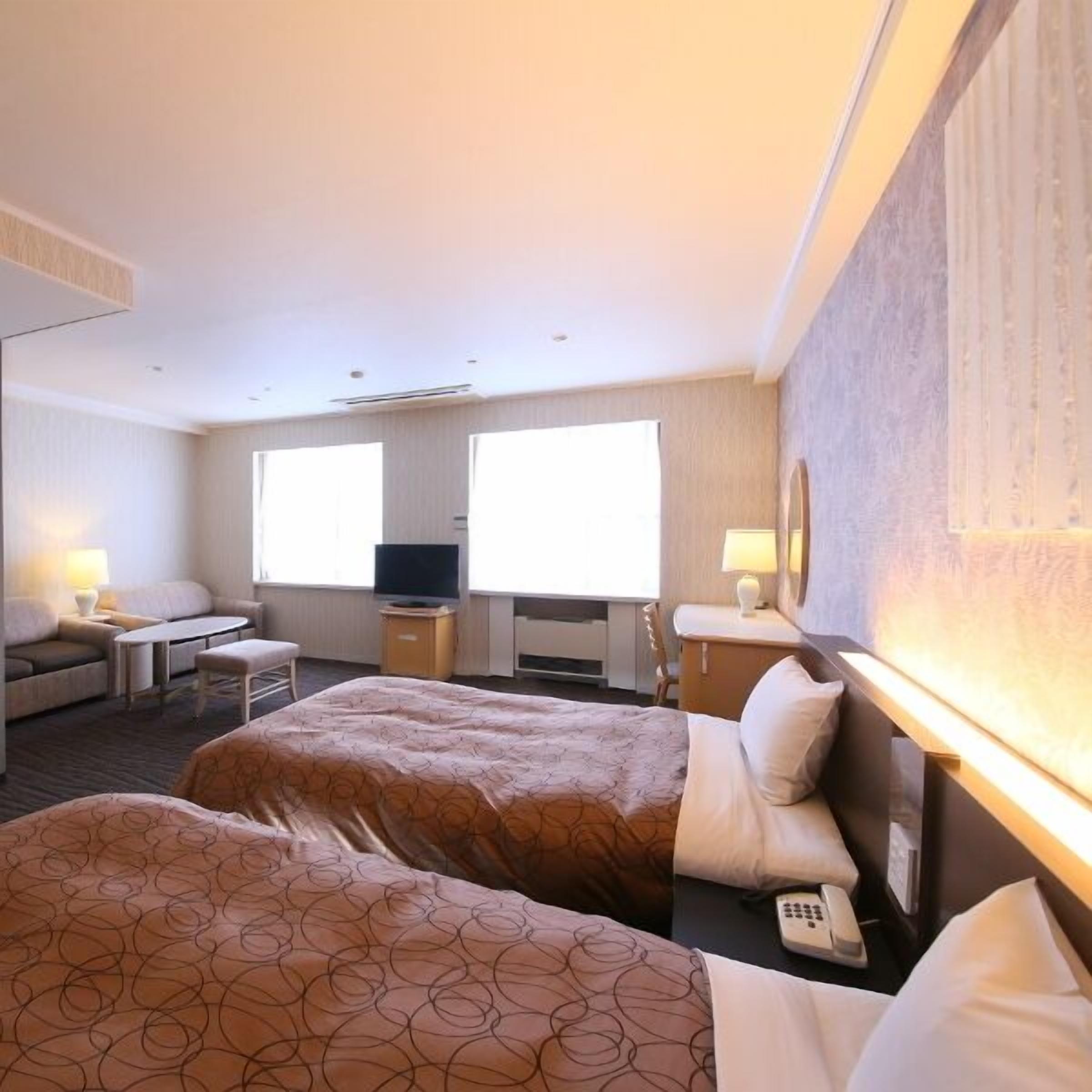 A hotel room with two beds, a TV, a desk, and a chair.