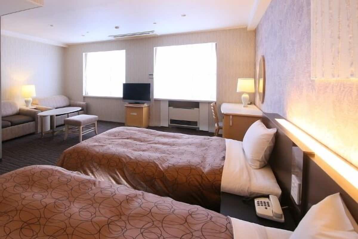 Una habitación de hotel con dos camas, un televisor, un escritorio y una silla.