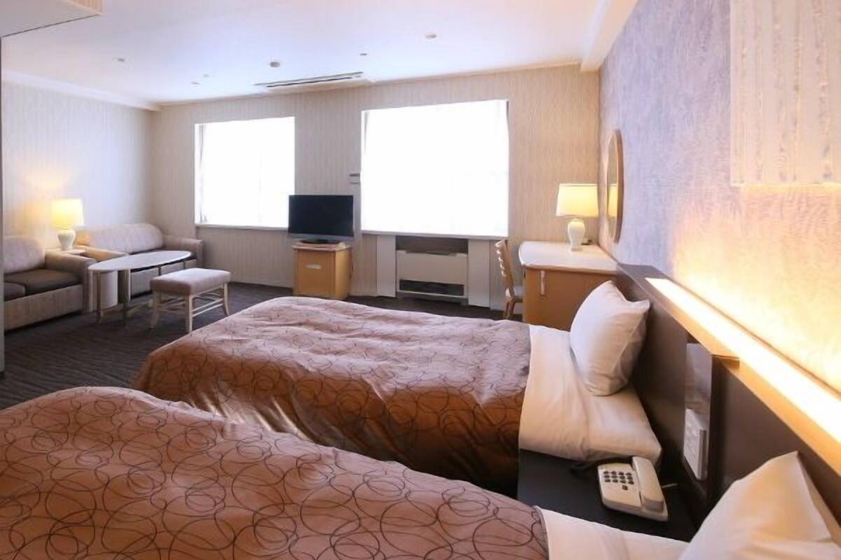 Una habitación de hotel con dos camas, un televisor, un escritorio y una silla.