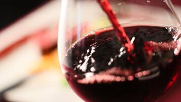 A close-up of a wine glass with red wine being poured into it.