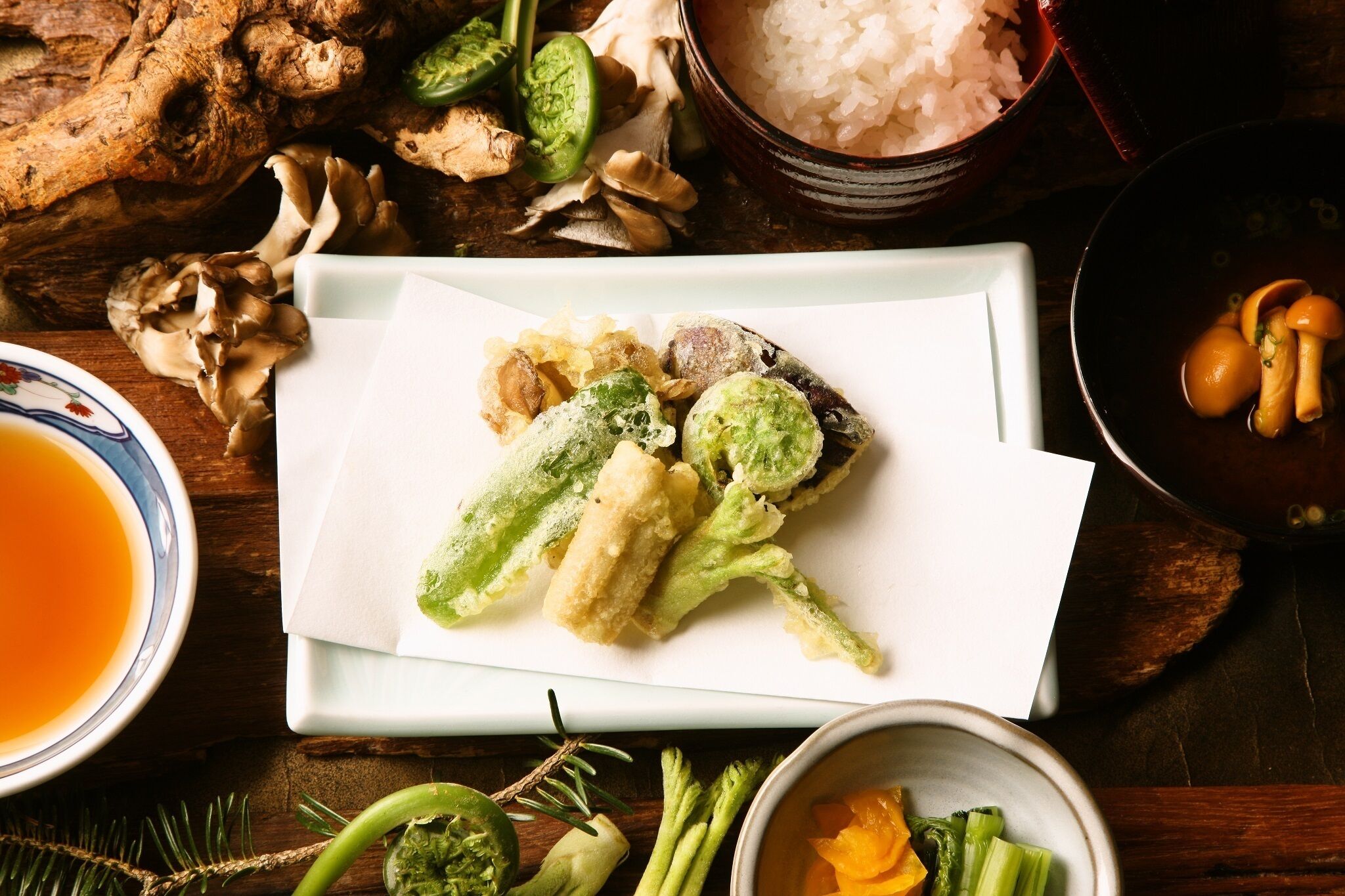 A dining table with various dishes, including fried vegetables and a bowl of rice.