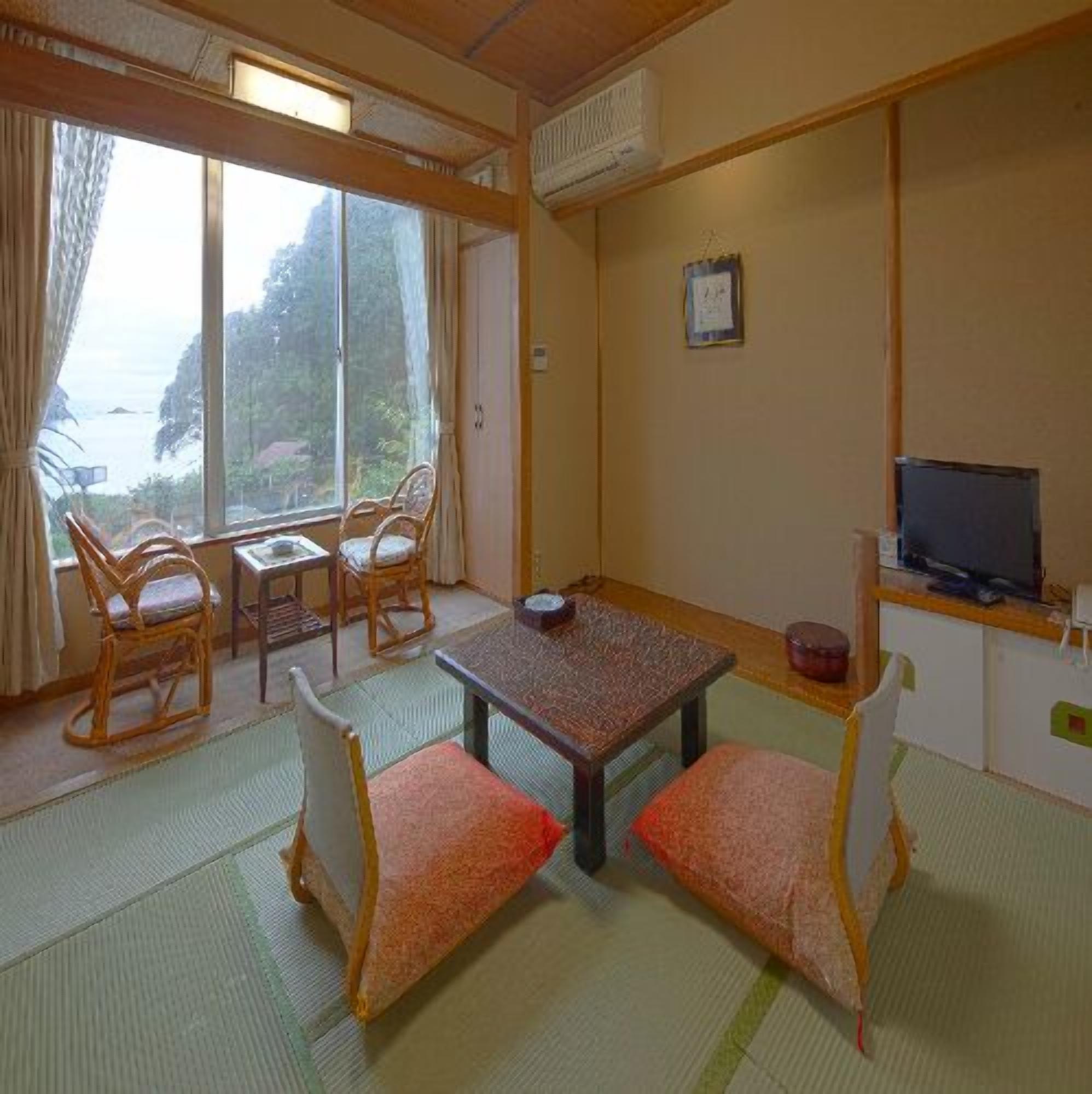 Una habitación con vista al mar, una mesa, sillas, un televisor y un mueble pequeño.