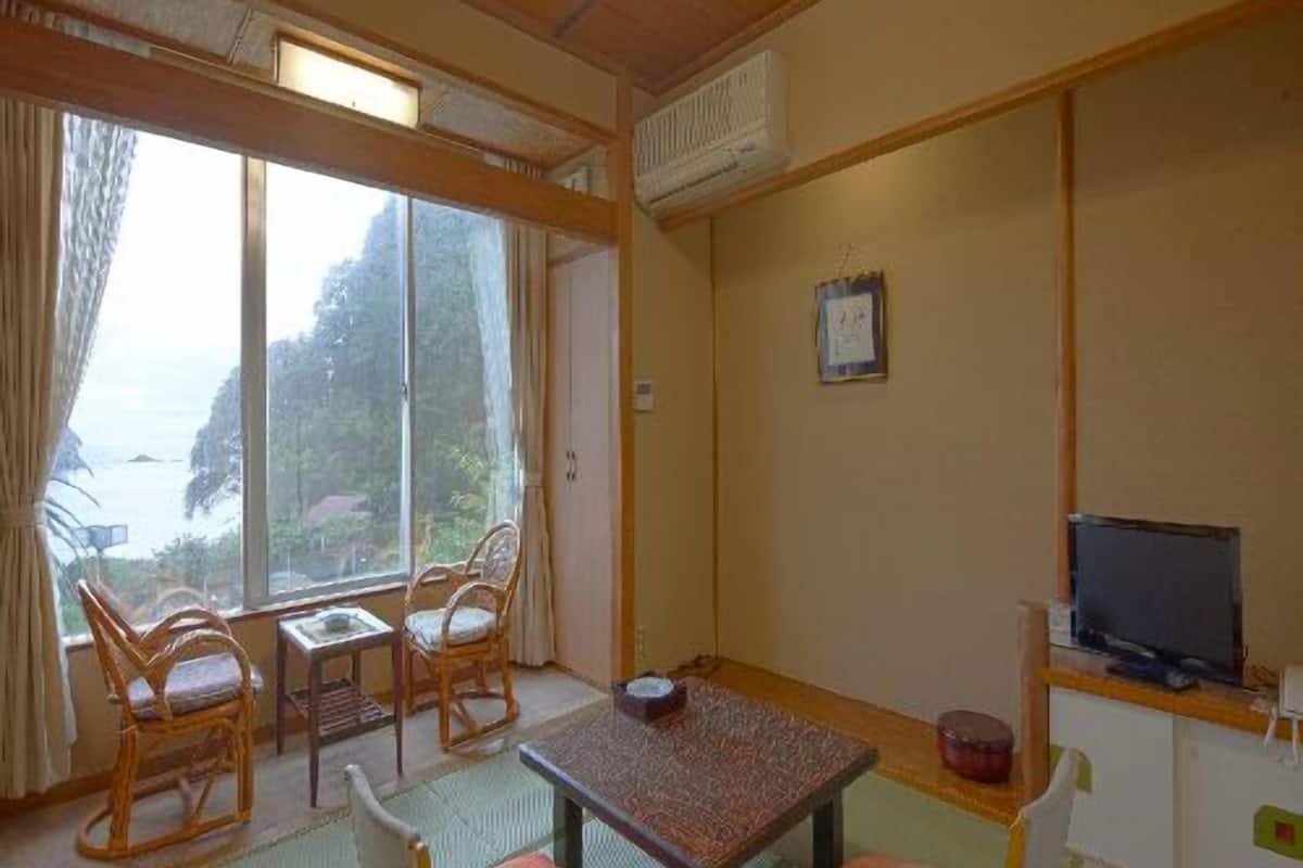 Une chambre avec vue sur la mer, une table, des chaises, un téléviseur et un petit meuble.