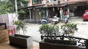 Une boutique appelée « Bunk Boutique », dont la devanture est fermée par un volet, avec des plantes en pot devant et des scooters garés.