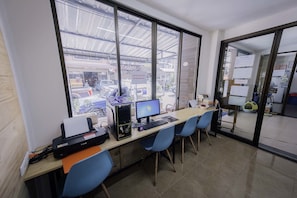 Un'area di lavoro con diversi computer, una stampante e sedie blu.