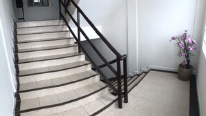 Un escalier avec des rampes en bois foncé et des carreaux de couleur beige.