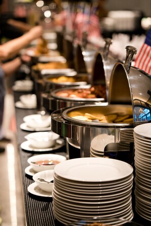 A buffet line with various food stations and stacked plates.