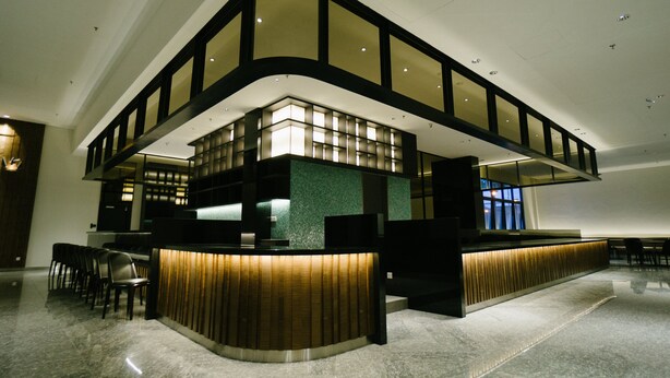 A modern hotel lobby with a curved reception desk, seating area, and a high ceiling with recessed lighting. - Avillion Cameron Highlands (Tanah Rata)