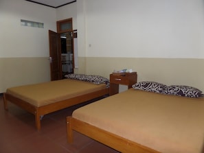 Una habitación con dos camas de madera, cada una con almohadas estampadas y una pequeña mesita de noche.