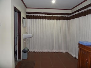 Un baño con un lavamanos blanco, un espejo, un cesto de basura y un armario de madera.