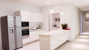 A modern kitchen with white cabinetry, stainless steel appliances, and pendant lighting.