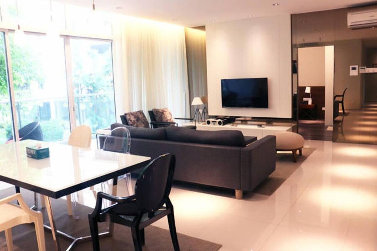 Un soggiorno moderno con un divano, una TV e un'area pranzo con tavolo e sedie.