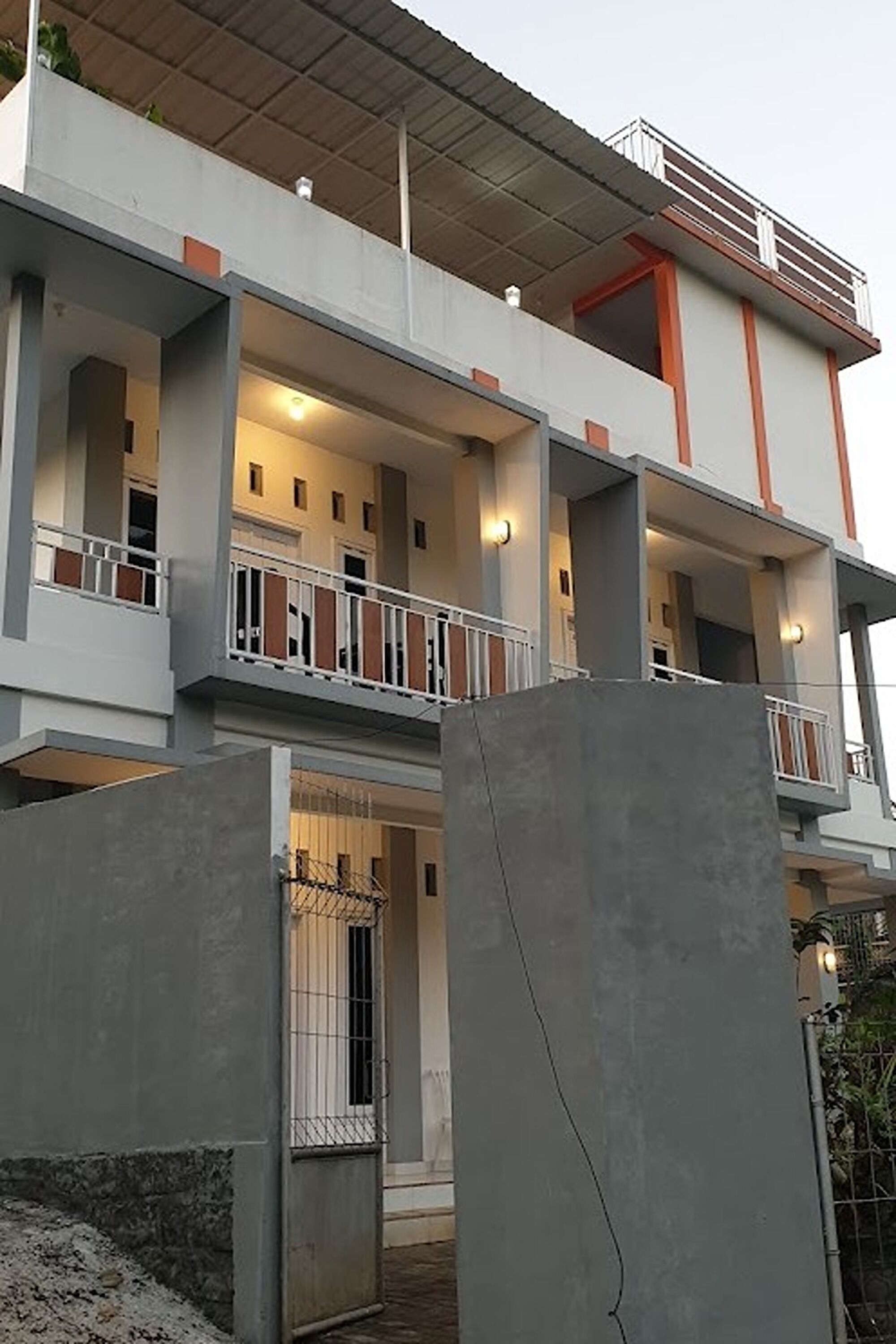 A multi-story building with balconies, a covered upper level, and a gated entrance.