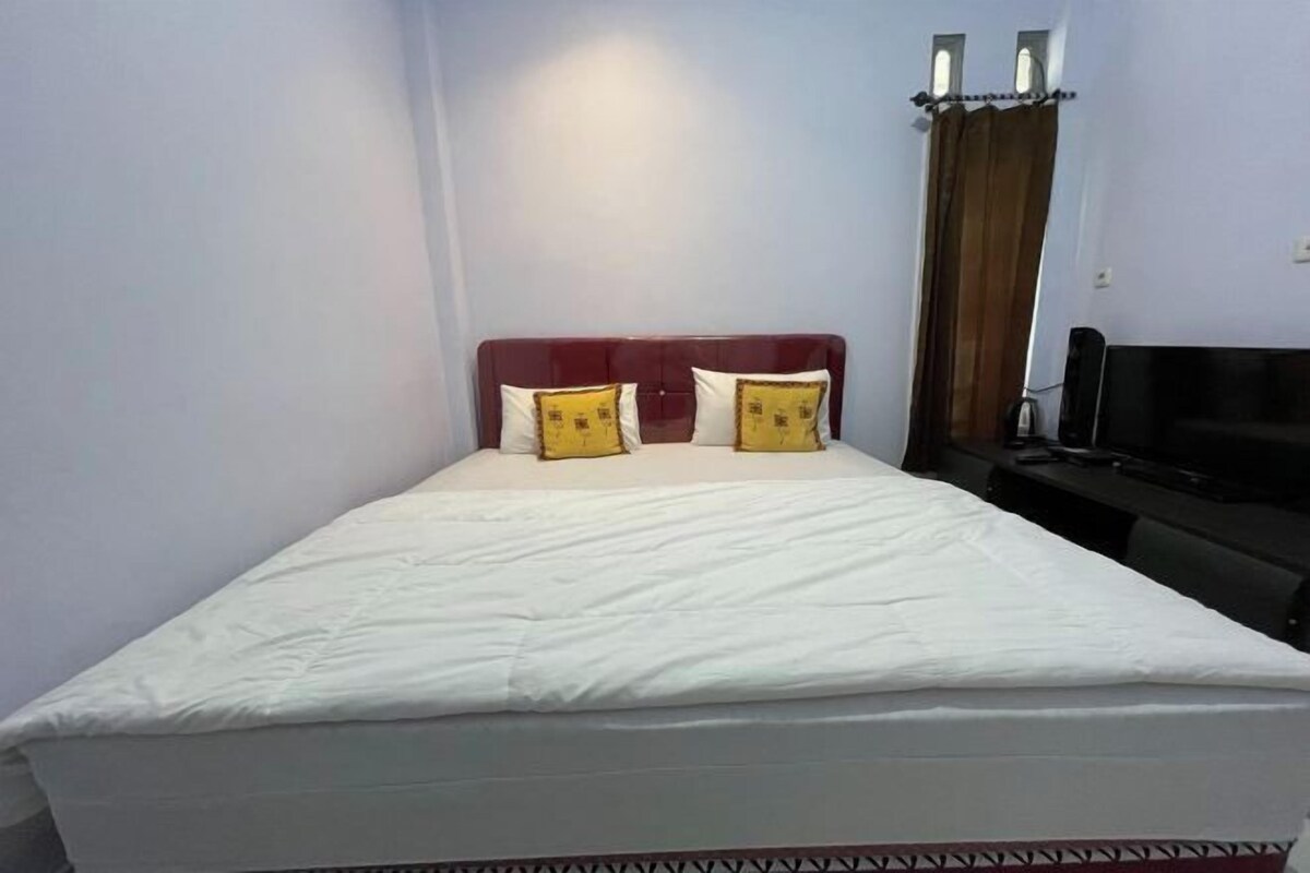 A hotel room with a single bed, a TV, and a curtain.