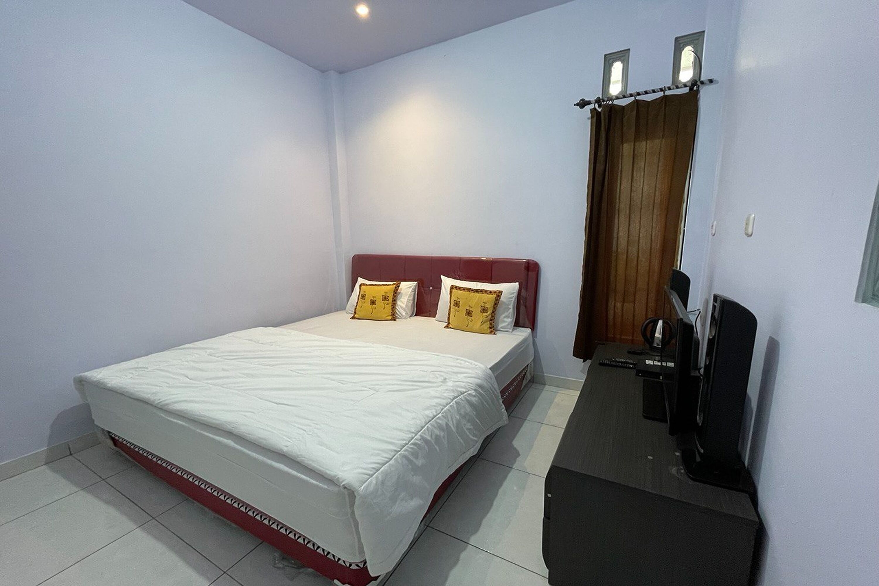 A bedroom with a bed, a TV, and a wooden door.