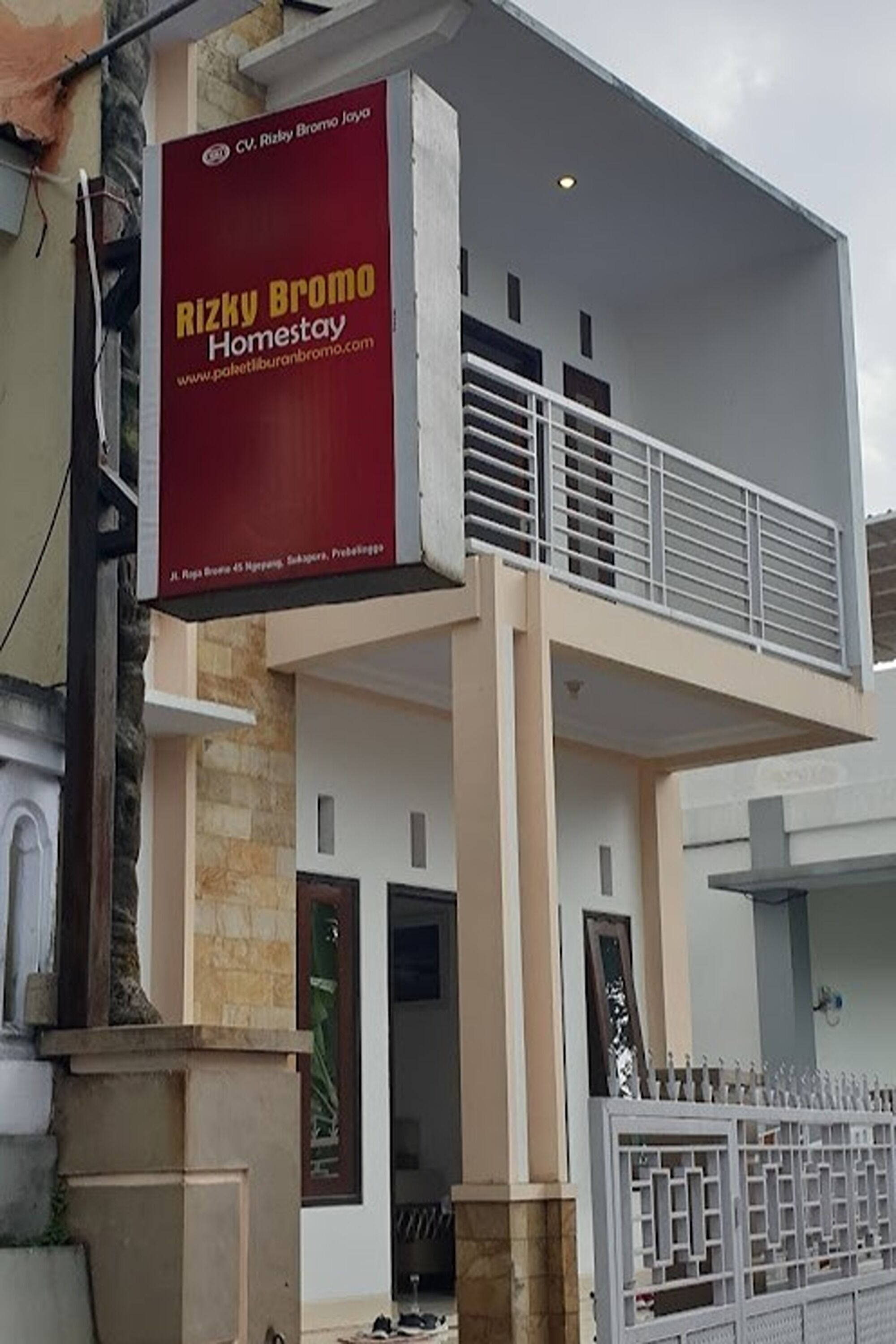 A modern two-story building with a balcony and a gated entrance.