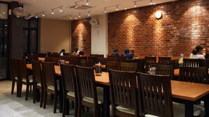 Un comedor con paredes de ladrillo, mesas y sillas de madera.