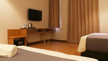 Una habitación de hotel con una cama, un escritorio, una silla, un televisor y una ventana con cortinas.