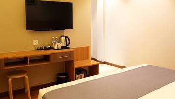 Una habitación de hotel con cama, escritorio, silla, televisión y cafetera.