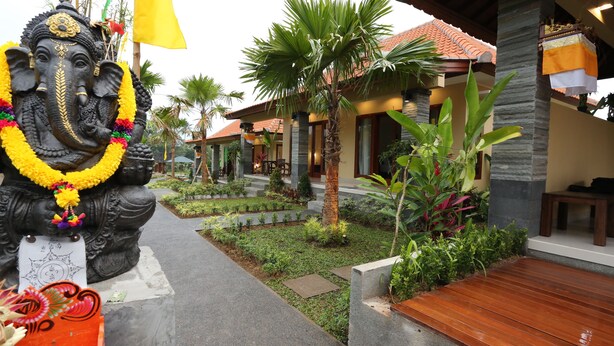 A courtyard with a statue of an elephant, palm trees, and a building with a tiled roof. - Darra Ria Villa Ubud (Ubud)