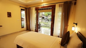 A hotel room with a bed, curtains, a view of the outside, and a small table. - Darra Ria Villa Ubud (Ubud)