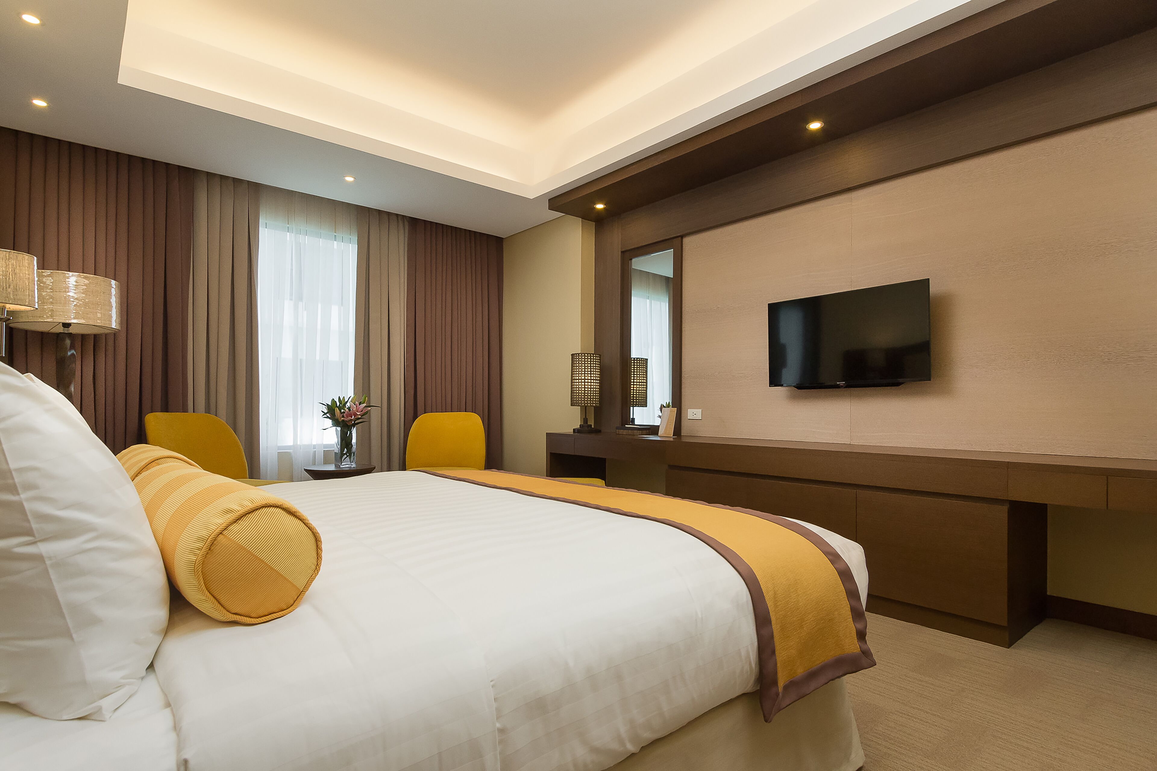 Een hotelkamer met een groot bed, een bureau met een flatscreen televisie, een stoel en een lamp.