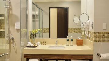 A bathroom with a glass shower enclosure, a sink with a mirror, and a towel rack.